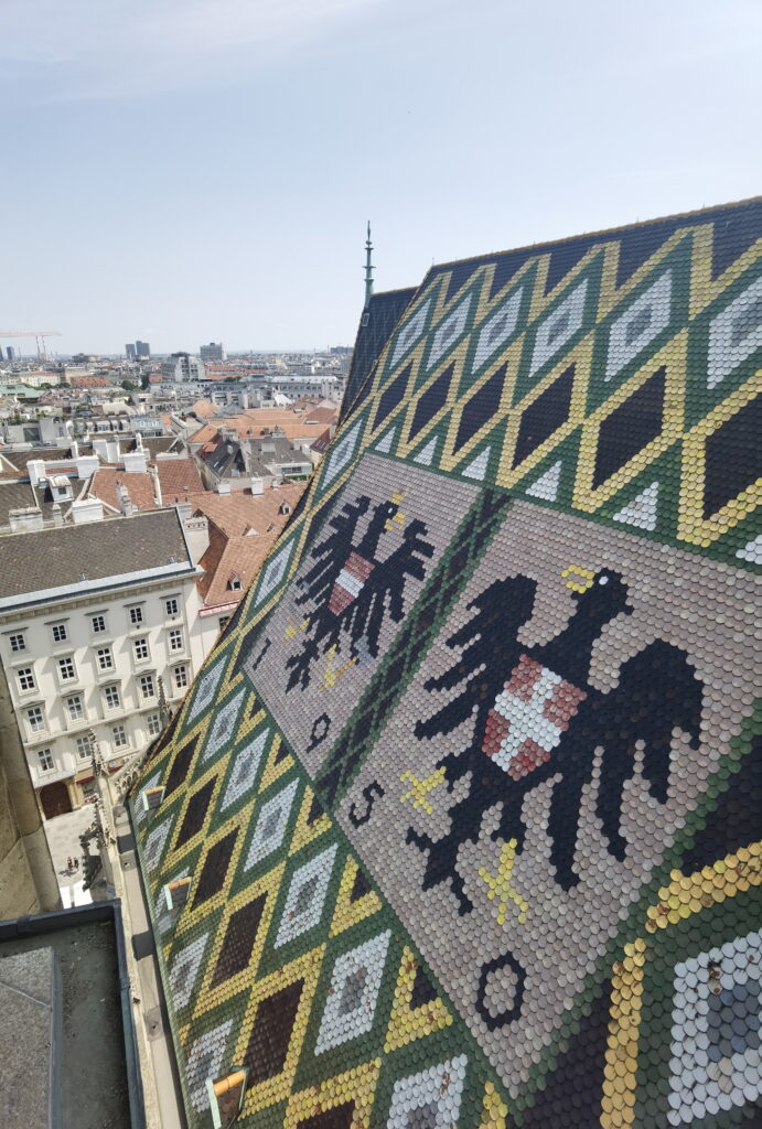 Von der Aussichtsplattform am Stephansdom Nordturm siehst du direkt auf das bunte Dach mit dem Doppeladler